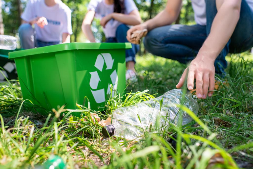 Cropped view of volunteers with recycling box cleaning lawn together